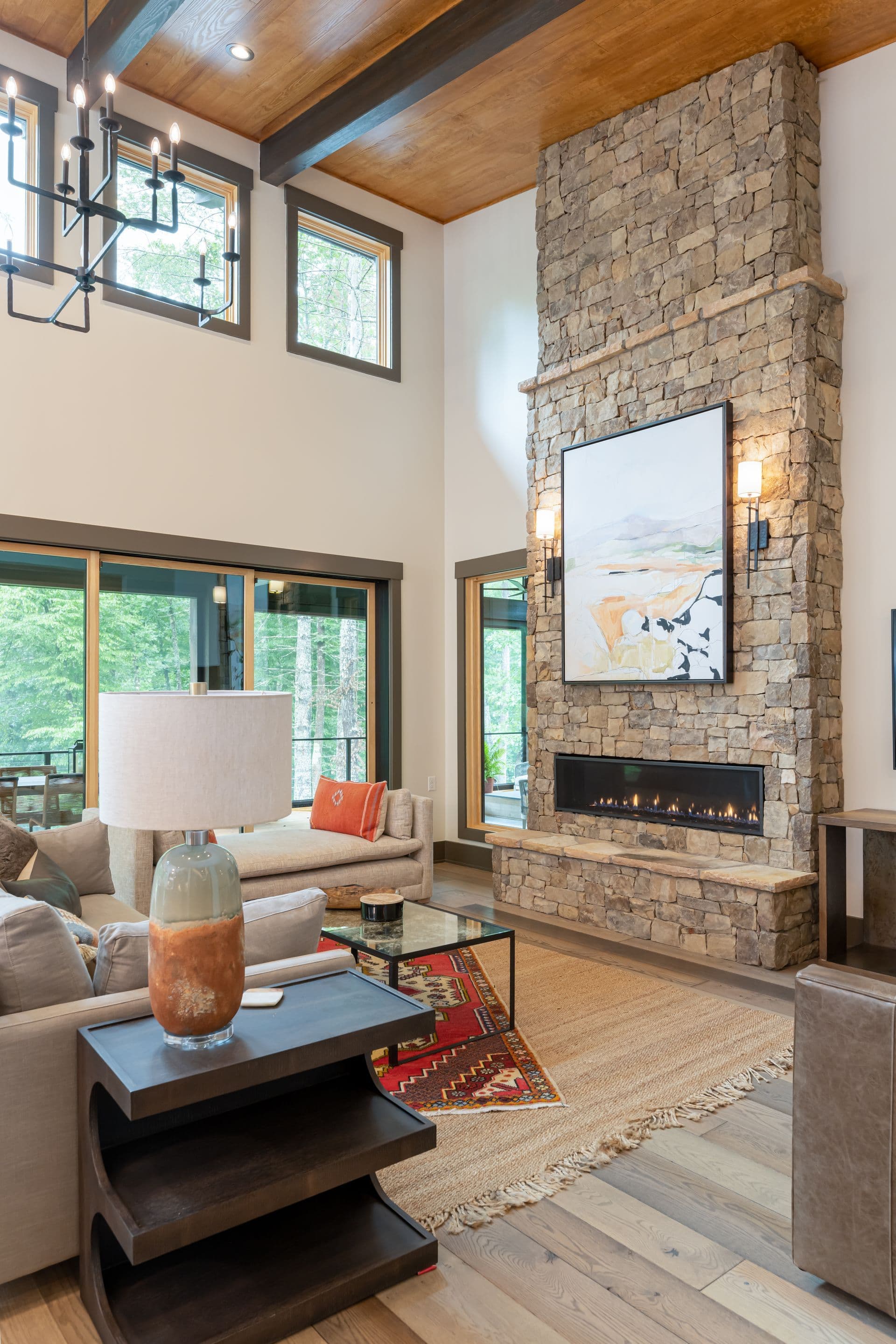 Double-height living room with a tall stone fireplace and timber ceiling