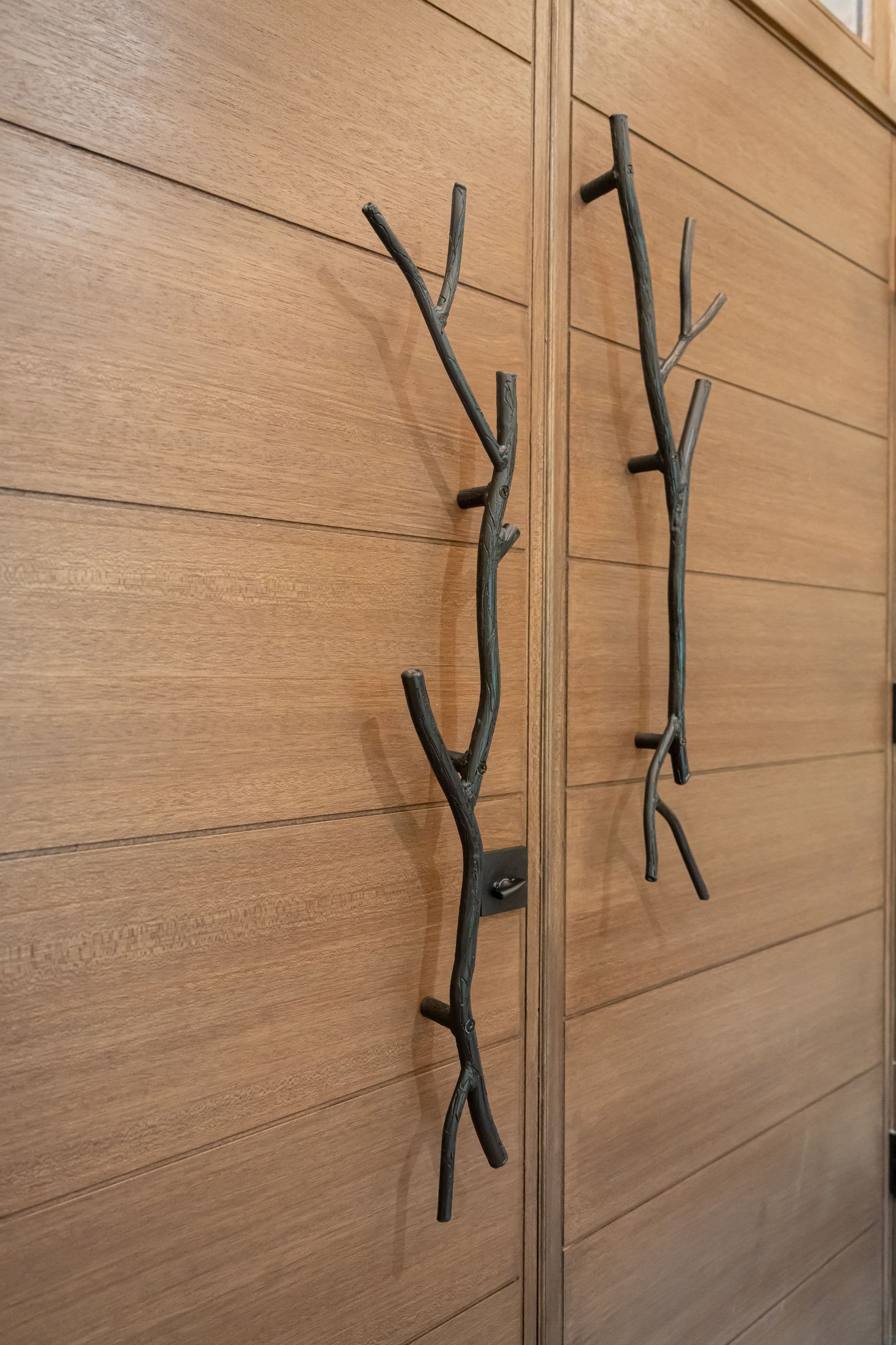 Natural wood front door with sculptural branch-shaped hardware
