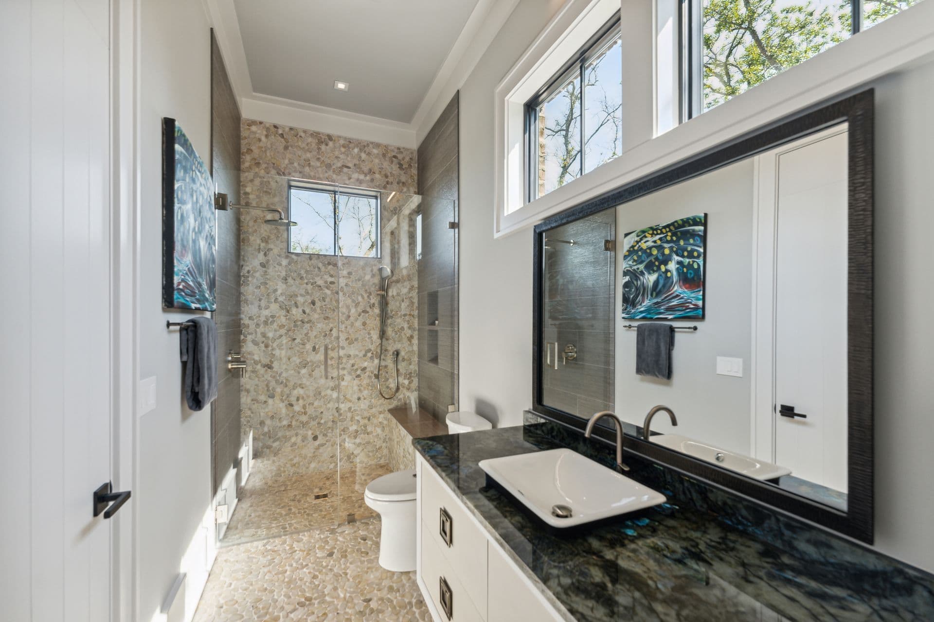 Glass shower and tiled bathroom with a window seat