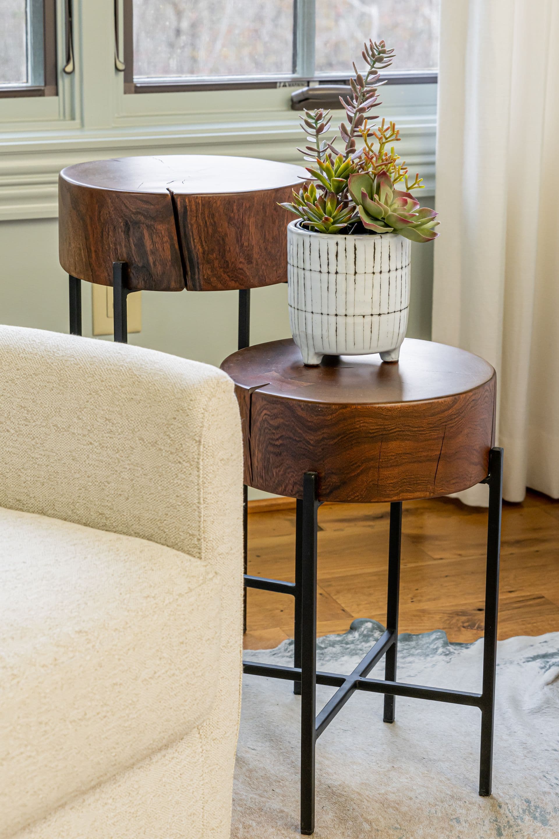 Pair of small tables styled with warm wood and collected objects